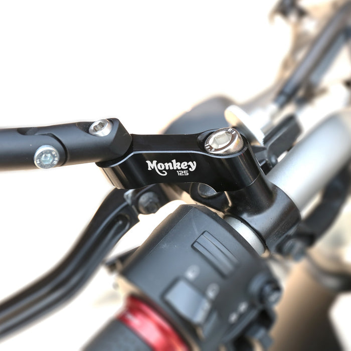 Black Honda Monkey 125 mirror extender riser by MC Motoparts installed on side mirror for improved visibility.