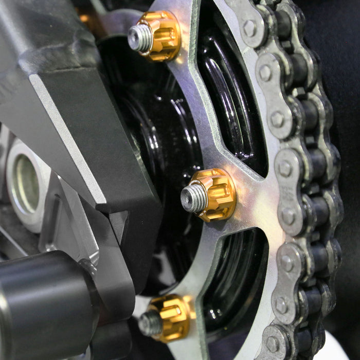 Six MC Motoparts Triumph Speed Triple 1050 rear sprocket nuts with billet M8 design on motorcycle wheel.
