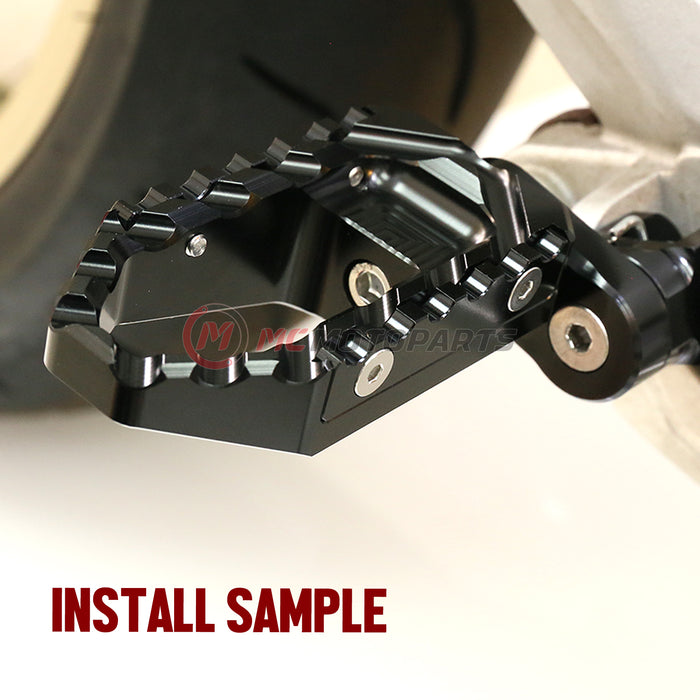 Front view of MC Motoparts 25mm extension foot pegs for Triumph Daytona 675 TRC touring motorcycle, showing black metal with mounting brackets.