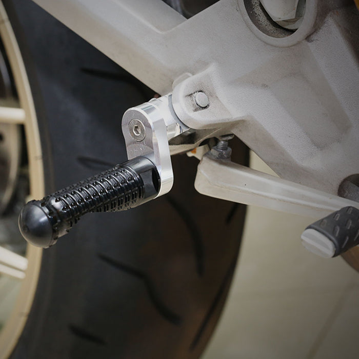 Black 25mm extension rear foot pegs for Honda CBR1000RR-R, CB125R, Rebel 500, by MC Motoparts, shown installed on motorcycle.